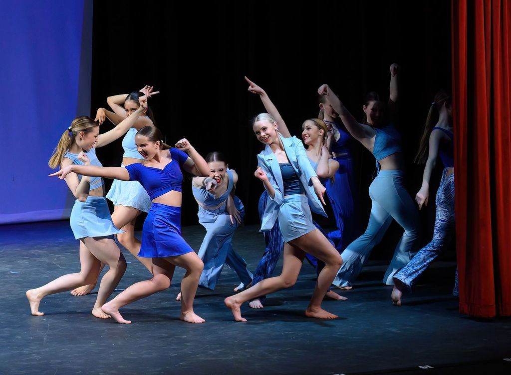 Competition team dancers in blue performing on stage